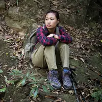 Seorang perempuan sedang duduk dan beristirahat saat mendaki gunung (Foto Dok: Freepik/jcomp).