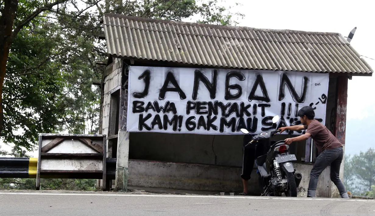 Warga memindahkan motor di Jalan Raya Puncak, Kabupaten Bogor, Jawa Barat, Minggu (19/4/2020). Arus lalu lintas di kawasan Puncak lengang seiring penetapan status Pembatasan Sosial Skala Besar untuk Kabupaten dan Kota Bogor pada Rabu (15/4) lalu. (Liputan6.com/Helmi Fithriansyah)