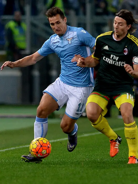 Penyerang Lazio, Miroslav Klose (kiri) berusaha melewati gelandang AC Milan, Riccardo Montolivo pada lanjutan liga serie A di Olimpico Stadium, Italia (1/2/2015). AC Milan menang atas Lazio dengan skor 1-3. (AFP PHOTO/TIZIANA FABI)