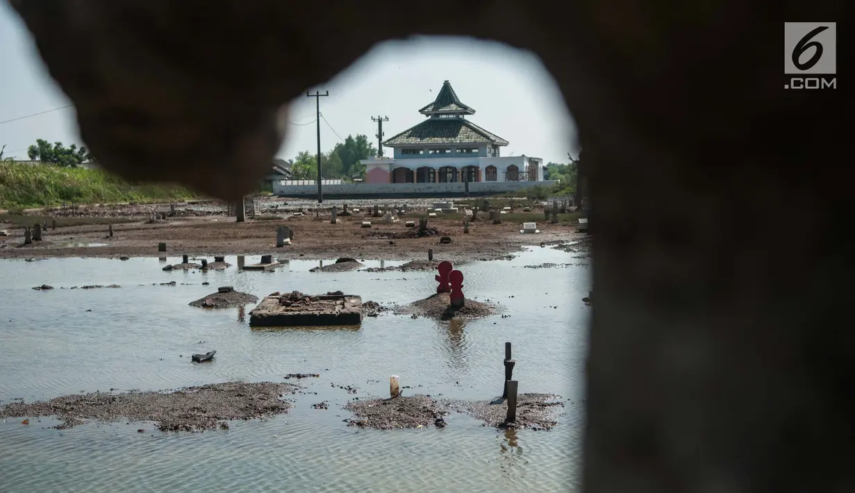 Suasana pemakaman yang terendam rob, di Desa Pantai Bahagia, Muara Gembong, Kabupaten Bekasi, Jawa Barat, Jumat (9/6). Banjir sering terjadi di kawasan tersebut dengan ketinggian air mencapai 50 cm.(Liputan6.com/Gempur M Surya)