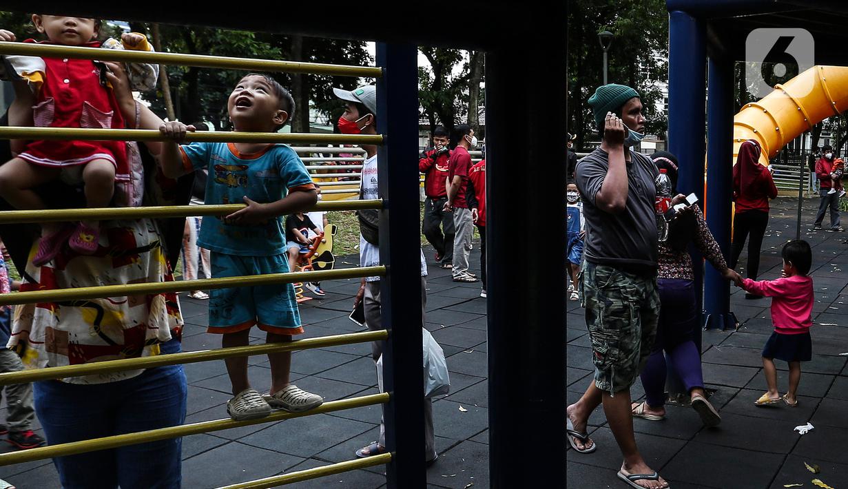 Anak-anak didampingi orang tua mereka bermain di Taman Puring, Jakarta, Minggu (9/1/2022). Di tengah ancaman penyebaran covid-19 varian Omicron dan pemberlakukan PPKM level 2, masyarakat tetap melakukan aktivitas pada akhir pekan di luar rumah. (Liputan6.com/Johan Tallo)