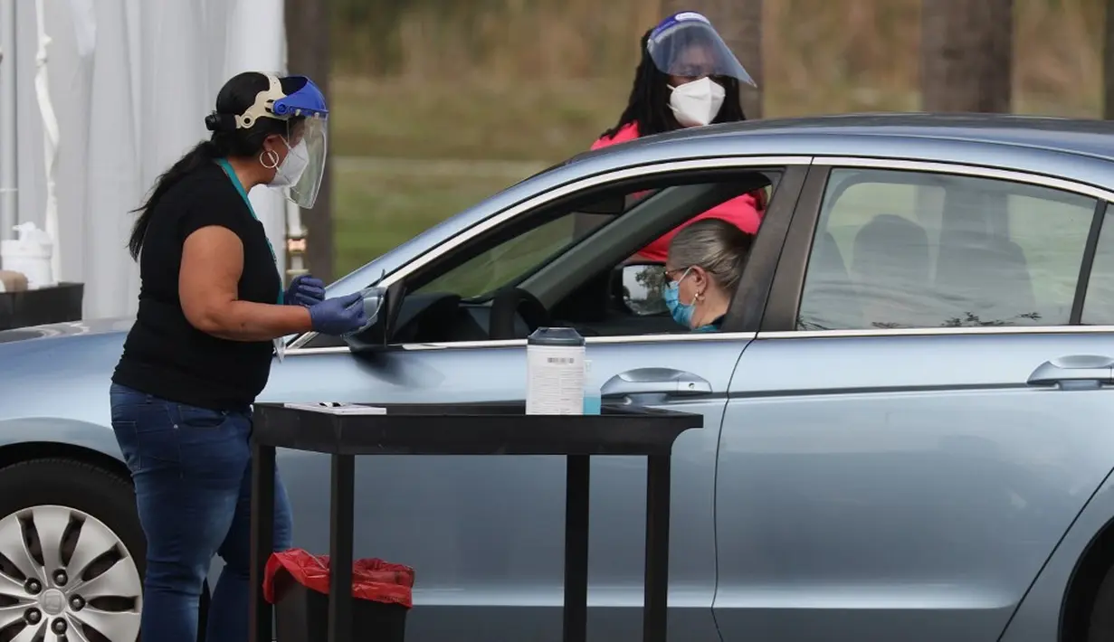Petugas kesehatan memeriksa warga sebelum mengarahkan ke area vaksinasi COVID-19 drive-thru di Vista View Park, Davie, Florida, Amerika Serikat, 4 Januari 2021. Lokasi vaksinasi COVID-19 drive-thru tersebut disiapkan untuk penduduk Broward yang berusia 65 tahun ke atas. (Joe Raedle/Getty Images/AFP)