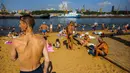 Orang-orang berjemur dan mendinginkan diri di Sungai Moskva pada musim panas di Moskow, Rusia, Selasa (13/7/2021). Moskow dilanda gelombang panas bersejarah pada akhir Juni, dengan suhu mencapai rekor 120 tahun. (DIMITAR DILKOFF/AFP)