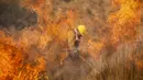 Petugas pemadam kebakaran memadamkan api di Capilla del Monte, Cordoba, Argentina (15/10/2020). Pada Rabu malam, hujan ringan memadamkan semua kebakaran di provinsi itu tetapi pada sore api kembali dengan suhu yang meningkat. (AP Photo/Mario Tizon)