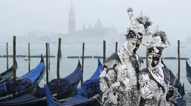 Dua orang peserta berpose di Piazza San Marco saat mengikuti Karnaval Venesia, Italia, Sabtu (30/1). Dalam acara tahunan ini, peserta mengenakan kostum ala Venesia abad ke-18 dan topeng-topeng unik menutupi wajah (REUTERS/Alessandro Bianchi)