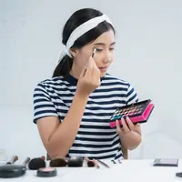 Ilustrasi seorang perempuan sedang makeup (copyright Freepik/Tirachardz)