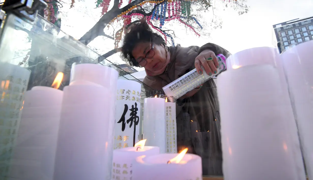 Seorang orang wanita menyalakan lilin untuk mendoakan keberhasilan anak dan kerabatnya dalam mengikuti tes kemampuan Skolastik College tahunan di Seoul (23/11). (AFP Photo/Jung Yeon-Je)
