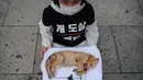 Seorang aktivis dari kelompok 'Animal Liberation Wave' dan 'Last Chance for Animals' membawa anak anjing mati yang diambil dari peternakan daging anjing di Gwanghwamun Plaza, Seoul (7/7). Mereka memprotes perdagangan daging anjing. (AFP Photo/Ed Jones)