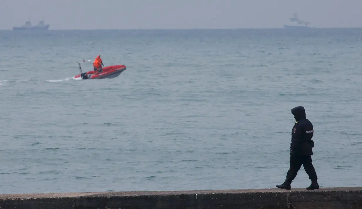 Seorang polisi berjalan di dermaga tidak jauh dari kecelakaan pesawat militer Rusia Tu-154 di Laut Hitam di pinggiran Sochi, Rusia (25/12). Sebanyak 91 penumpang belum diketemukan dalam kecelakaan pesawat. (REUTERS/Maxim Shemetov)