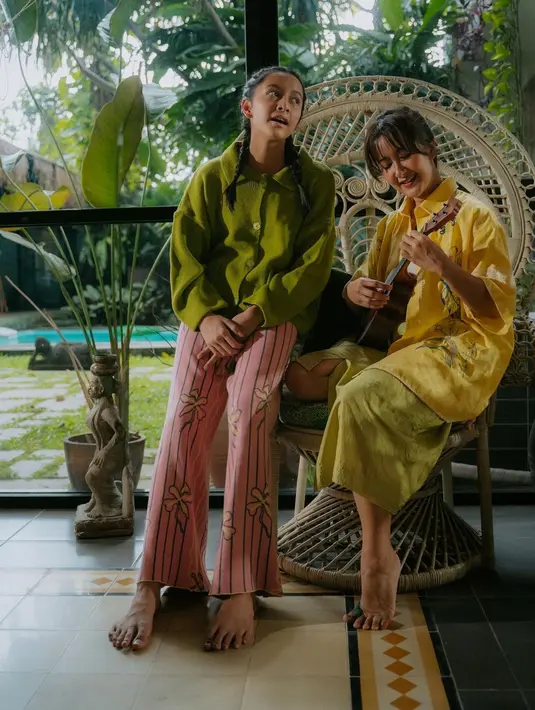 Ada lagi potret kebersamaan keduanya dalam balutan busana yang lebih kasual. Widi Mulia dengan gitar kecil mengenakan atasan berwarna kuning dan celana bernuansa kehijauan. Sedangkan Widuri bernyanyi di sebelahnya dengan kemeja lengan panjang berwarna hijau dan paduan celana panjang bernuansa merah muda bermotif floral. Foto: Instagram.