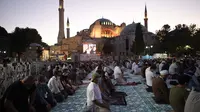 Umat Islam, memanjatkan doa-doa mereka selama salat Idul Adha, dengan latar belakang Hagia Sophia, yang baru-baru ini dikonversi kembali ke masjid, di distrik bersejarah Sultanahmet di Istanbul, 31 Juli 2020.  (AP Photo/Yasin Akgul)