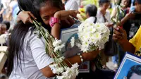 Kerabat korban korban penumpasan narkoba Presiden Rodrigo Duterte satu sama lain di pemakaman di kota Quezon pada bulan Maret. (AP/Bullit Marquez)