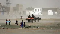 Anak-anak Afghanistan bermain saat badai pasir di pinggiran Kabul, Afghanistan (25/8/2020). Sebuah badai pasir hebat melanda Kabul. Badai menyebabkan jarak pandang jadi berkurang. (AP Photo / Rahmat Gul)