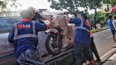 Pekerja tengah mengepak sepeda motor yang akan dikirim melalui jasa pengiriman dengan kereta api di Kawasan Stasiun Senen, Jakarta, Kamis (13/4/2023).(Liputan6.com/Angga Yuniar)