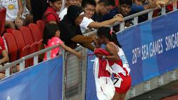 Triyaningsih mencium tangan sang bunda setelah meraih emas nomor lari 5.000m SEA Games yang berlangsung di Stadion Nasional Singapura. Selasa (9/6). (Bola.com/Arief Bagus)