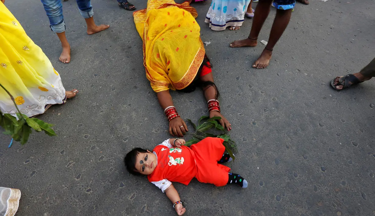 Seorang anak diletakan di jalan saat mengikuti festival keagamaan Chhat Puja di Kolkata, India (6/11). Ritual ini bertujuan untuk mencari berkah, meminta kesejahteraan, dan kemakmuran dari Dewa Matahari. (Reuters/Rupak De Chowdhuri)