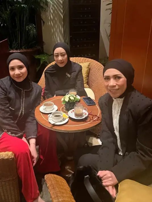 Hijab lilit yang dikenakan Nagita Slavina dipadukan dengan blazer hitam Chanel dan celana merah [@raffinagita1717]