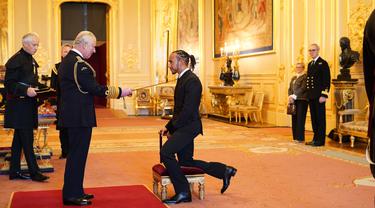 Pembalap Lewis Hamilton, menerima gelar kebangsawanan dari Pangeran Charles untuk prestasinya di bidang olahraga, di Kastil Windsor, Rabu (15/12/2021). Pemegang gelar juara dunia balapan Formula Satu tujuh kali ini diberi gelar Knight Bachelor. (Dominic Lipinski/PA via AP)