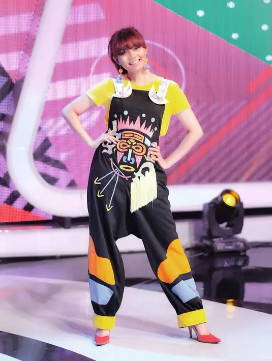Masih dengan busana yang colorful, kali ini Rina memakai jumpsuit bermotif karakter wajah. Ia pun juga memadukan dengan kaus berwarna kuning dan heels warana oranye. Sungguh merona kan tampilannya? (Instagram/rinanose16)