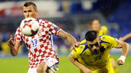 Duel pemain Kroasia, Mario Madzukic (kiri) dengan pemain Kosovo, Bajram Jashanica pada laga Grup I kualifikasi Piala Dunia 2018 di Stadion Maksimir, Zagreb, (2/9/2017).  Laga tersebut diberhentikan wasit karena stadion penuh genangan air. (AFP/ STR)