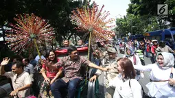 Gubernur DKI Jakarta Djarot Saiful Hidayat bersama istri Happy Farida menaiki delman sambil melambaikan tangan kepada warga dan pegawai Pemprov DKI Jakarta saat perpisahan dirinya di Balaikota DKI Jakarta, Minggu (15/10). (Liputan6.com/Immanuel Antonius)