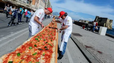 Sejumlah koki ahli berupaya mencetak rekor dunia dengan membuat pizza terpanjang di dunia, di sepanjang pinggir Laut Naples, Italia, 18 Mei 2016. Pizza itu memiliki ukuran sekitar 1 mil dan terbentang di sepanjang pinggir Laut Naples. (Mario LAPORTA/AFP)