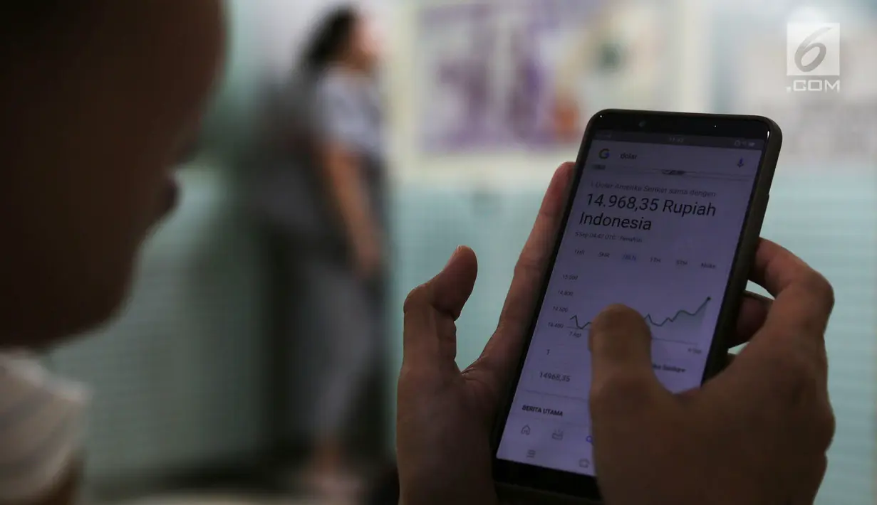 Warga mengecek nilai tukar Rupiah terhadap USD menggunakan ponselnya di gerai penukaran mata uang asing di Jakarta, Rabu (5/9). Nilai tukar Rupiah di pasar spot menguat tipis 0,06 persen ke Rp 14.926 per dollar Amerika. (Merdeka.com/Imam Buhori)