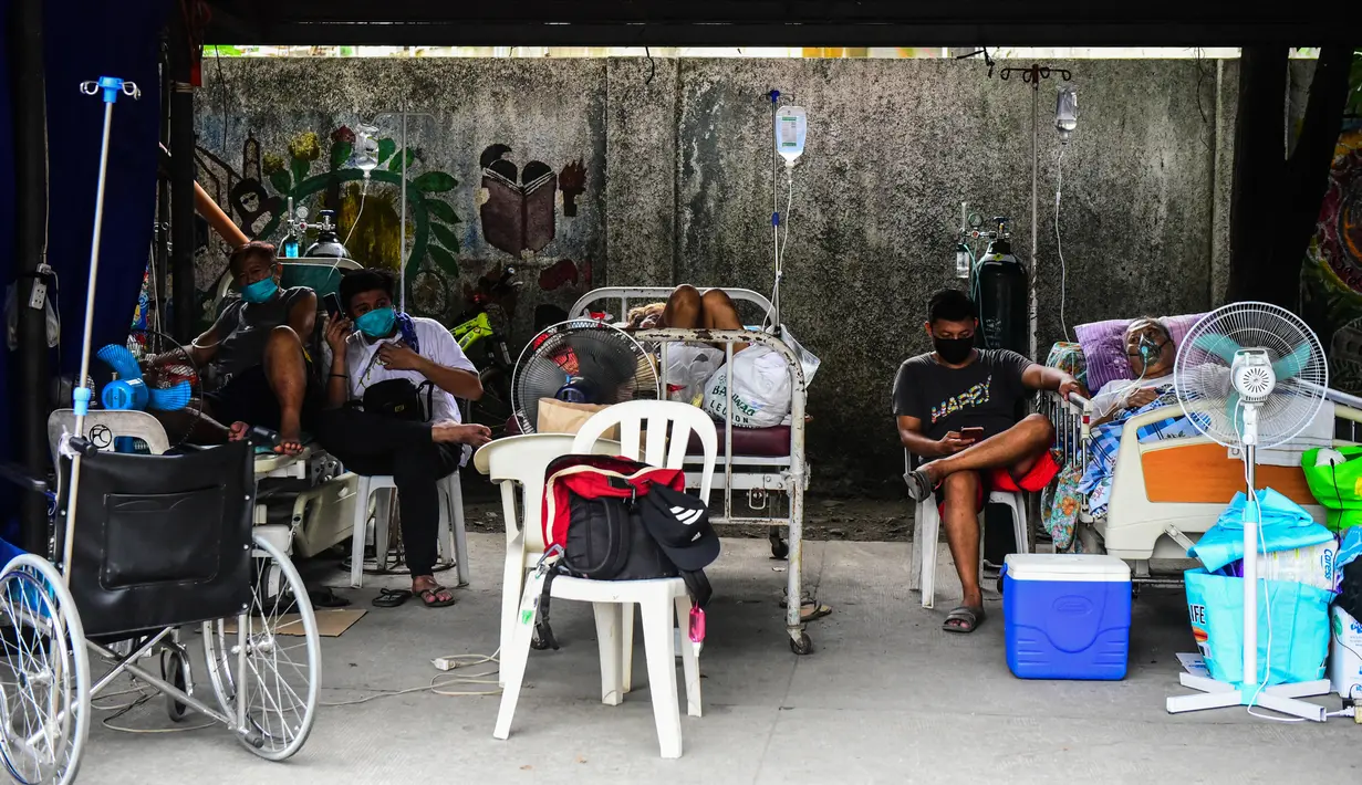 Pasien dan kerabat terduga Covid-19 beristirahat di tempat parkir yang diubah menjadi bangsal di luar rumah sakit di kota Binan, provinsi Laguna, Manila, di tengah rekor infeksi yang dipicu oleh varian Delta yang sangat menular pada Senin (6/9/2021). (Photo by Maria Tan / AFP)