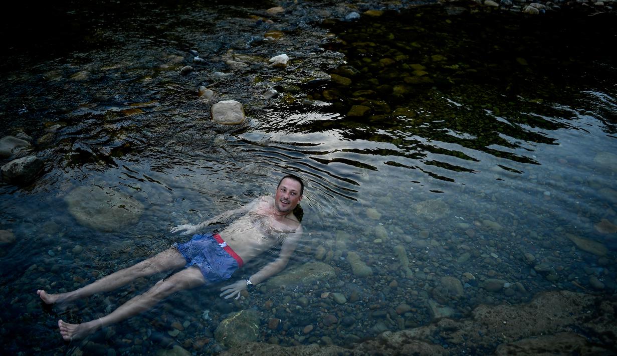 Seorang pria berendam sambil menikmati pemandian air panas alami Sungai Cidaco dengan suhu 52 Celcius saat pagi musim dingin di desa kecil Arnedillo, Spanyol utara, 29 Desember 2018. (AP Photo/Alvaro Barrientos)