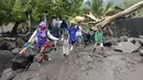 Orang-orang berjalan di tengah puing-puing di sebuah desa yang terkena banjir di Ile Ape, di Pulau Lembata, provinsi Nusa Tenggara Timur, Minggu (4/5/2021).  sejumlah ruas jalan dan jembatan rusak akibat banjir bandang tersebut. . (AP Photo/Ricko Wawo)