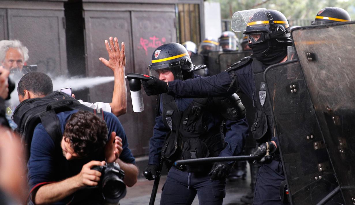 Polisi anti huru-hara menyemprotkan gas ke demonstran dan para fotografer saat terjadi bentrokan di Paris, Prancis (23/5). Para pekerja layanan publik Prancis melakukan pemogakan dan meluas menjadi aksi protes. (AP/Christophe Ena)