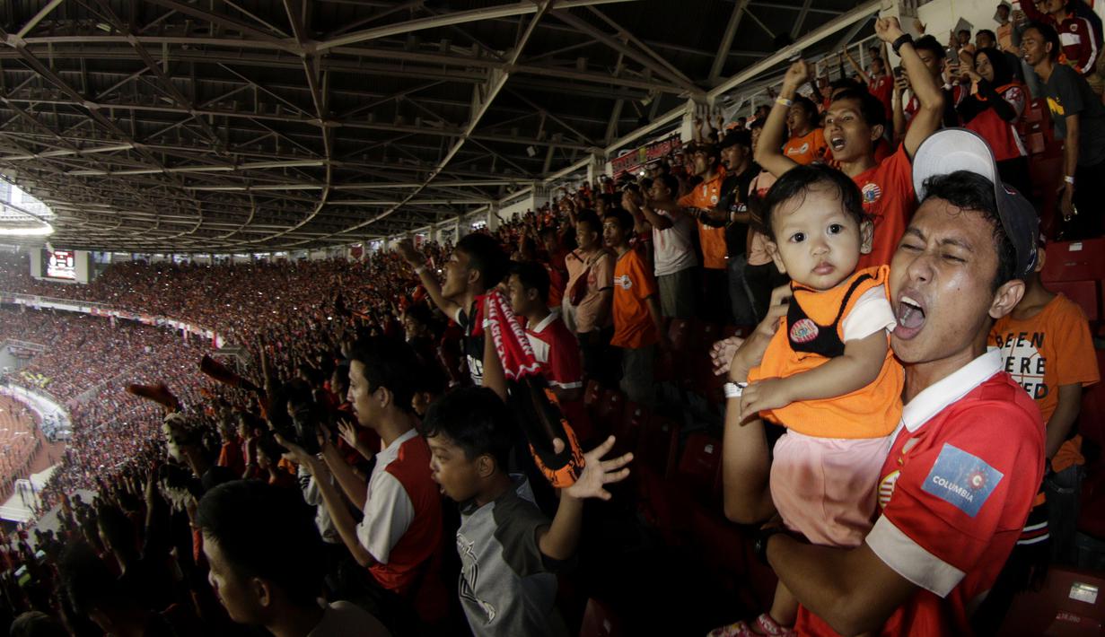 Suporter Persija Jakarta menggendong anaknya saat merayakan gelar juara Liga 1 di SUGBK, Jakarta, Minggu (09/12). Persija menang 2-1 atas Mitra Kukar. (Bola.com/M Iqbal Ichsan)