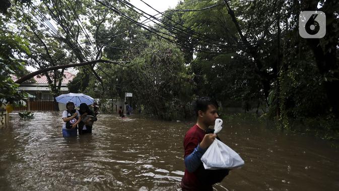 Warga melintasi banjir di Jalan Hang Lekir, Kebayoran Lama, Jakarta Selatan, Rabu (1/1/2020). Banjir tersebut disebabkan karena tingginya intensitas hujan yang mengguyur sejak Selasa (31/12/2019). (Liputan6.com/Johan Tallo)