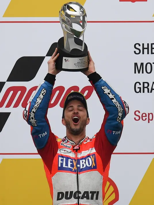 Pembalap Ducati Team, Andrea Dovizioso mengangkat pialanya setelah berhasil memenangkan MotoGP Malaysia di sirkuit Sepang, Minggu (29/10). Dovizioso menyelesaikan balapan dengan catatan waktu 44 menit 51.497 detik. (Manan VATSYAYANA / AFP)