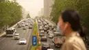 Seorang wanita yang memakai masker wajah berjalan melintasi jembatan penyeberangan saat badai pasir di Beijing, China, Kamis (6/5/2021). Debu dan badai pasir akhir musim semi mengirim indeks kualitas udara melonjak di Ibu Kota China pada hari ini. (AP Photo/Mark Schiefelbein)