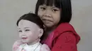 Prew menggendong boneka Look Thep (anak malaikat) di sebuah toko di department store, Bangkok, Thailand, Selasa (26/1). Boneka yang diisi dengan roh anak kecil melalui ritual tertentu itu dipercaya bisa membawa keberuntungan (REUTERS/Athit Perawongmetha)