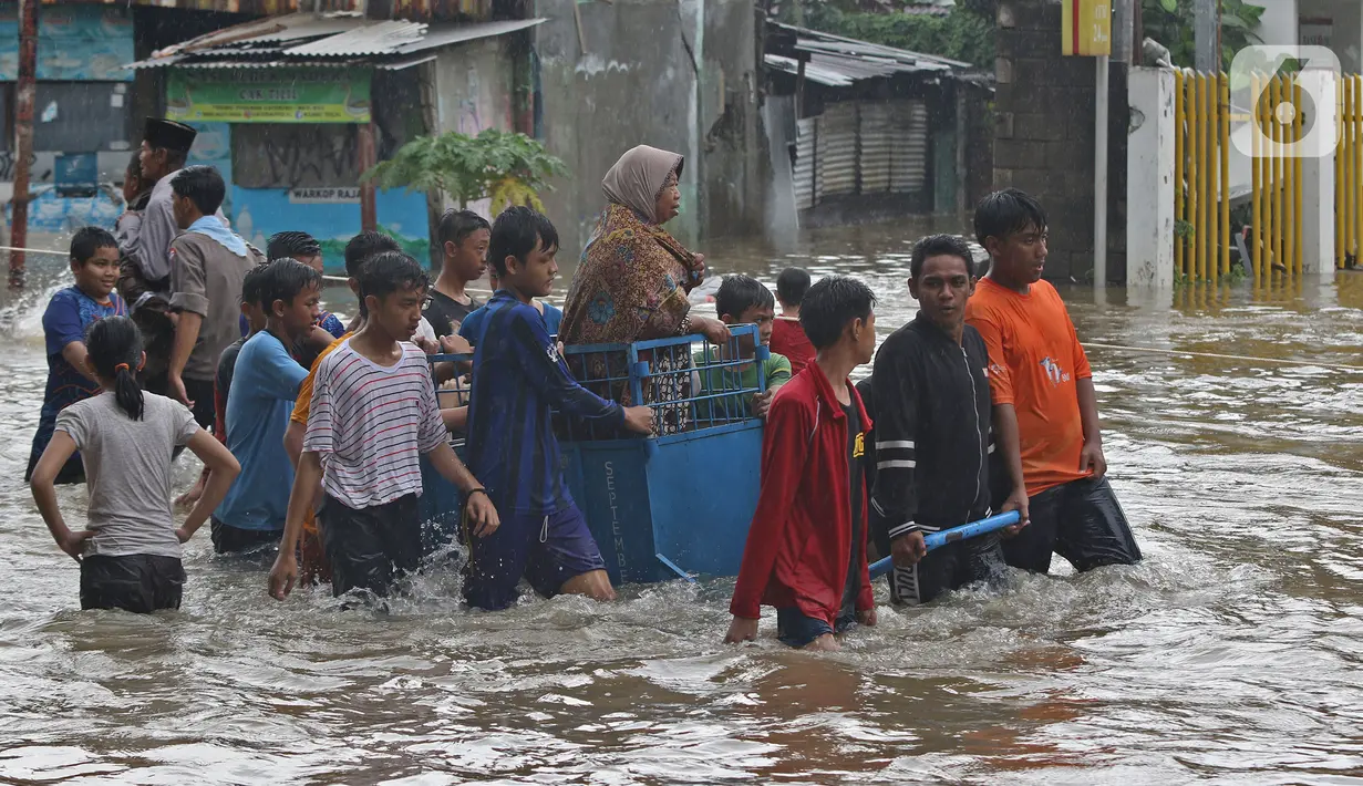 Warga menggunakan jasa gerobak untuk menghindar banjir yang merendam Jalan Pondok Raya Gede, Jakarta Timur, Selasa (25/2/2020).  Sejumlah ruas jalan tergenang dan akses ke beberapa wilayah terputus, salah satunya Jalan Pondok Raya Gede. (Liputan6.com/Herman Zakharia)