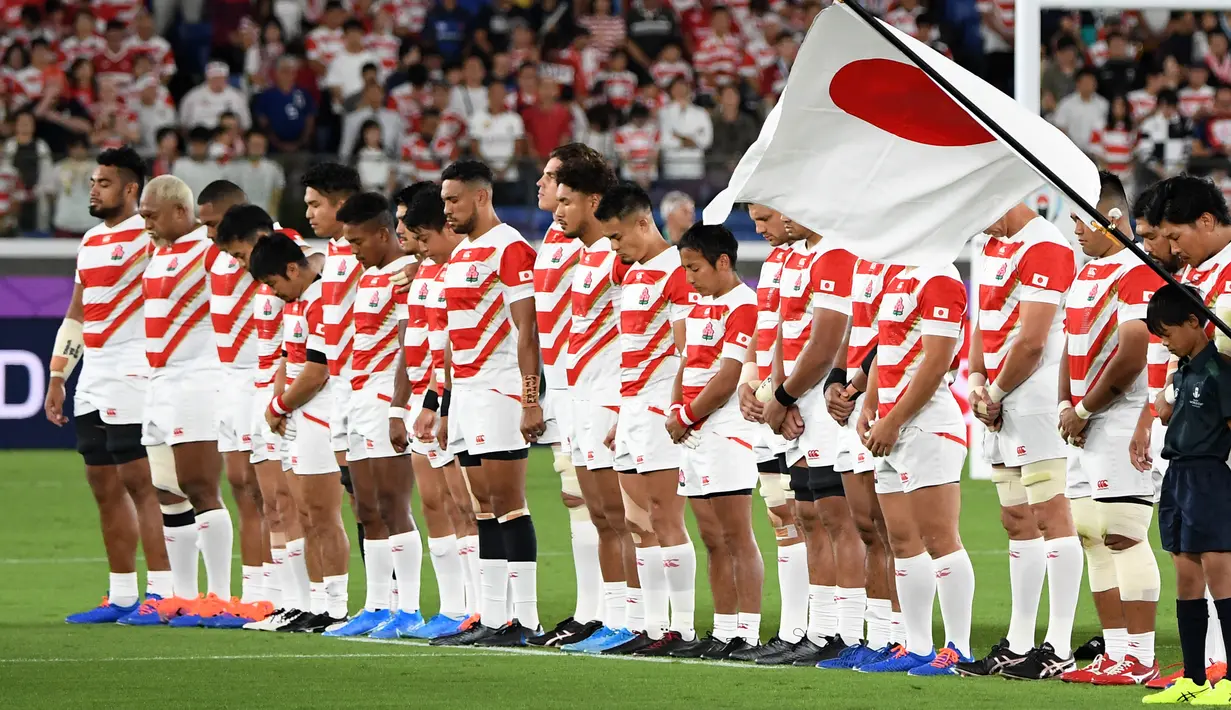 Pemain rugby Jepang berdoa untuk korban Topan Hagibis sebelum melawan Skotlandia di Piala Dunia Rugbi 2019 di Stadion Internasional Yokohama (13/10/2019). Sebelumnya Topan Hagibis menerjang wilayah Jepang bagian utara termasuk Tokyo, pada Minggu pagi, (13/10). (AFP Photo/William West)
