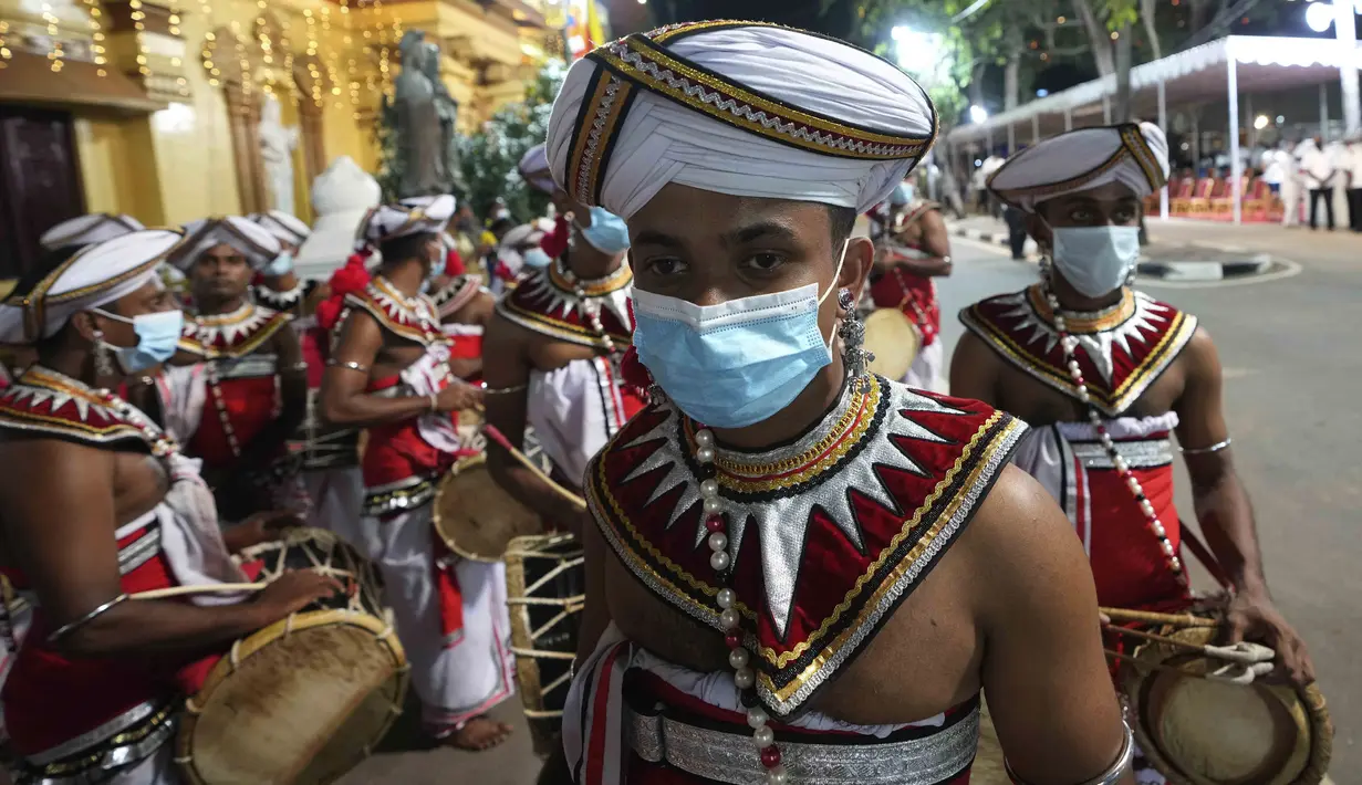 Penabuh genderang tradisional mengenakan masker untuk melindungi diri dari COVID-19 saat menunggu untuk tampil pada Festival Navam Perahera di Kolombo, Sri Lanka, 15 Februari 2022. Biksu, penari, pemusik, dan lainnya berpartisipasi dalam perayaan di Kuil Gangaramaya. (AP Photo/Eranga Jayawardena)
