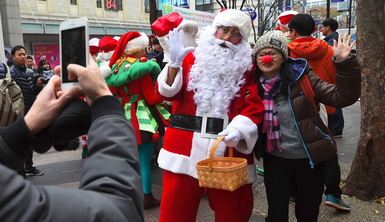 Seorang wanita FOTO bersama Santa Claus saat promosi musim Natal di distrik perbelanjaan di Seoul (13/11). Meski sebagian besar penduduknya adalah umat Budha, anak muda Korsel menikmati perayaan musim Natal tersebut. (AFP Photo/Jung Yeon-Je)