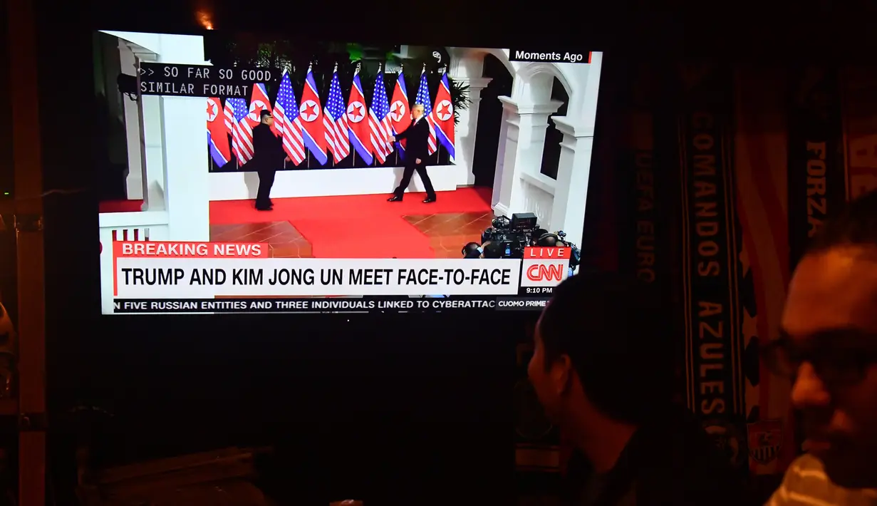 Seorang pria menonton berita pertemuan pemimpin Korea Utara Kim Jong-un dengan Presiden AS Donald Trump di sebuah bar Airedale, Washington, Selasa (12/6). Untuk pertama kalinya dalam sejarah, Donald Trump dan Kim Jong-un bertemu. (AFP PHOTO/Nicholas Kamm)