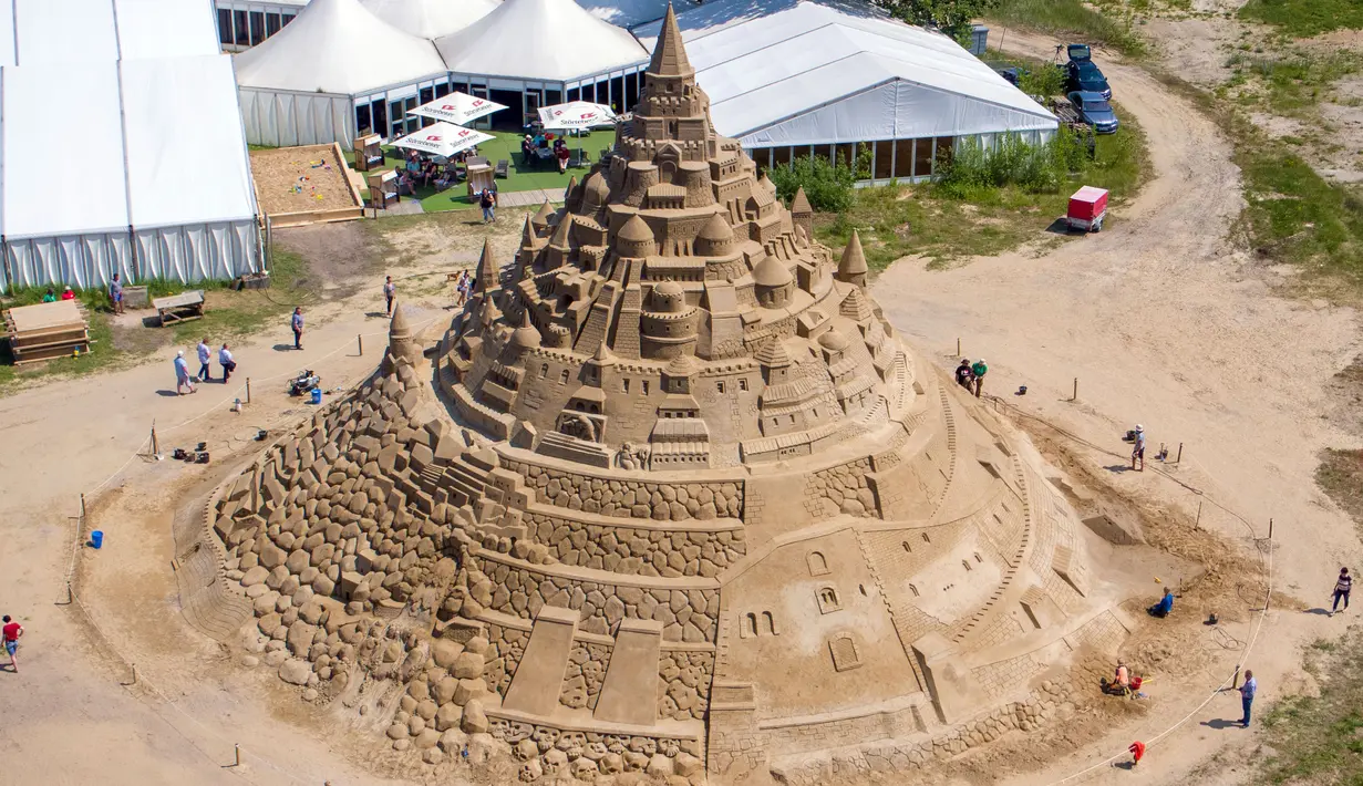 Pemahat beraktivitas di istana pasir tertinggi pada kompetisi tahunan "Sand Sculptures Festival" di Binz, Pulau Reugen di Laut Baltik, Jerman, 5 Juni 2019. Kompetisi sandcastle ini sendiri telah menjadi agenda tahunan pada kalender sosial Binz sejak tahun 2010. ( Jens Buettner/dpa via AP)