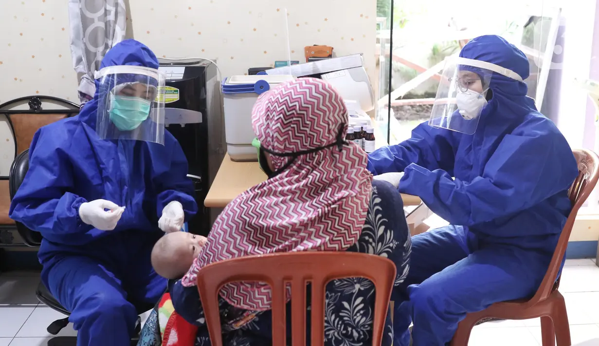 Bidan mengenakan alat pelindung diri (APD) saat melakukan imunisasi kepada bayi di Puskesmas Karawaci Baru, Tangerang, Banten, Rabu (13/5/2020). Pelayanan imunisai sesuai jadwal ini diberikan kepada bayi untuk menambah kekebalan imun tubuh. (Liputan6.com/Angga Yuniar)