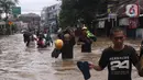 Warga melintasi banjir yang merendam Benhil, Jakarta, Selasa (25/2/2020). Hujan yang mengguyur wilayah tersebut membuat air sungai meluap sehingga menyebabkan Banjir setinggi pinggang orang dewasa. (Liputan6.com/Angga Yuniar)
