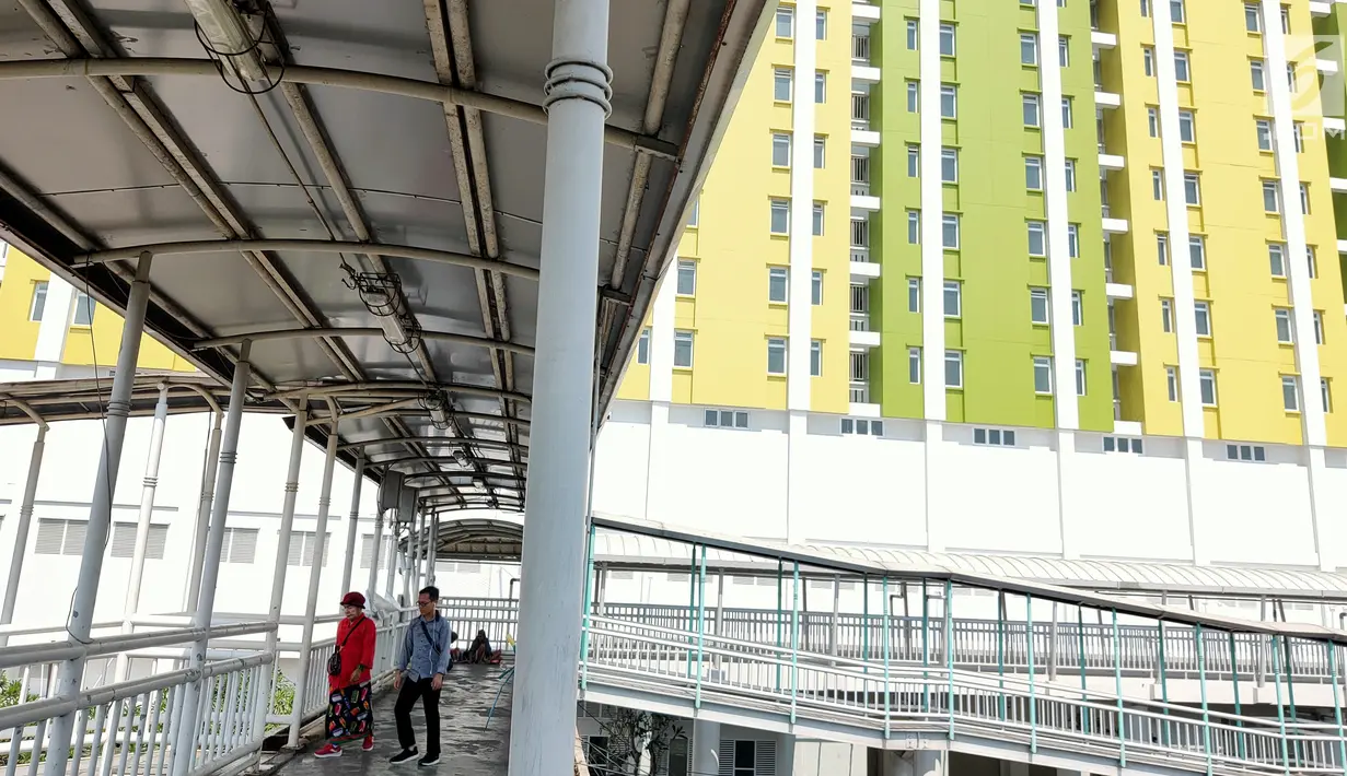 Pejalan kaki melewati jembatan penyeberangan orang (JO) dekat proyek Rusunawa Pasar Rumput yang hampir selesai pengerjaannya di Jakarta, Selasa (16/7/2019). Proyek yang dimulai sejak 2016 lalu tersebut memiliki 1.984 unit hunian serta 1.314 kios. (Liputan6.com/Immanuel Antonius)