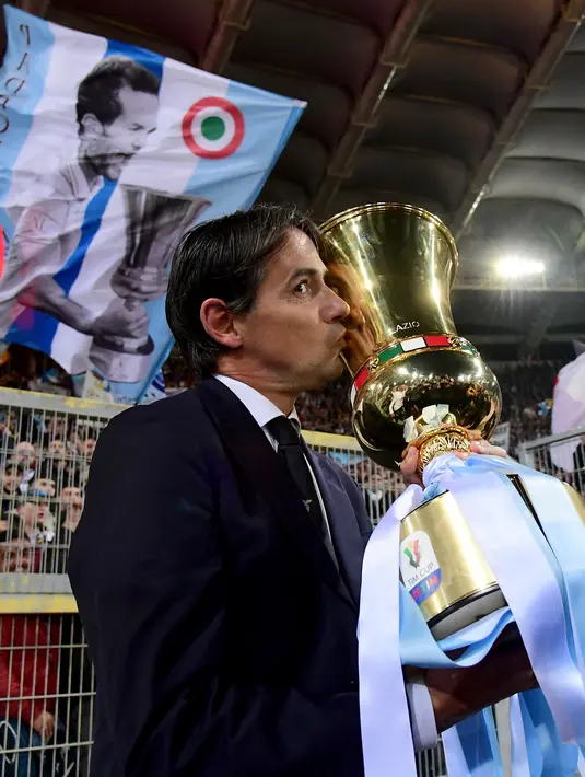 Pelatih Lazio Simone Inzaghi mencium trofi Piala Tim saat merayakan kemeangnan atas Atalanta pada final Coppa Italia di Stadion Olimpiade di Roma pada 15 Mei 2019. Inter resmi menunjuk Inzaghi sebagai pelatih baru menggantikan Conte. (AFP/Vincenzo Pinto)