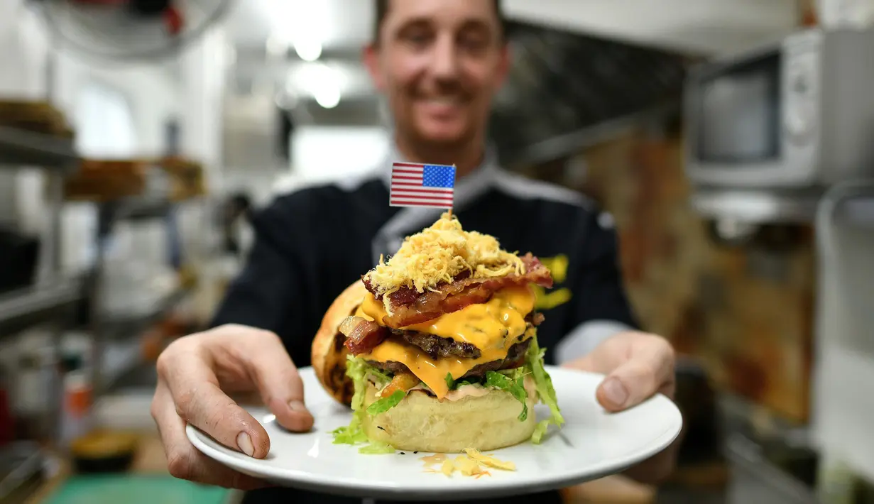 Koki Irlandia, Colin Kelly berpose dengan burger "Durty Donald" di restoran Durty Bird, Hanoi, Vietnam, 21 Februari 2019. Menu baru ini terinspirasi pertemuan puncak antara Presiden AS Donald Trump dan pemimpin Korut, Kim Jong-un. (Manan VATSYAYANA/AFP)