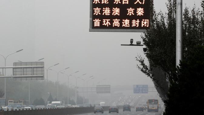 Suasana lalu lintas sebuah jalan yang diselimuti kabut asap tebal di Beijing, China (14/11). Pihak berwenang mengeluarkan peringatan kuning untuk polusi udara buruk pada hari Rabu. (AP Photo/Andy Wong)
