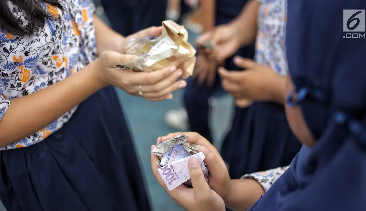 Para murid mendapat uang saat hujan uang di lapangan SMP Angkasa Halim Perdana Kusuma, Jakarta, Kamis (7/6). Hujan uang ini dalam rangka pre-launching buku milik motivator bisnis Tung Desem Waringin berjudul "LIFE REVOLUTION." (Liputan6.com/Faizal Fanani)