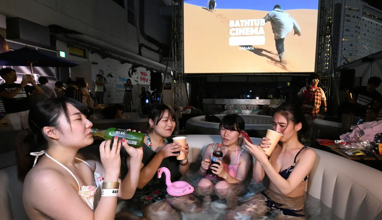 Pengunjung menikmati menonton film sambil berendam di Bathtub Cinema di atap gedung kawasan Shibuya, Tokyo, 17 Agustus 2018. Bathtub Cinema merupakan solusi kreatif yang ditawarkan oleh Afro&Co. untuk menikmati Tokyo di musim panas. (AFP/Kazuhiro NOGI)